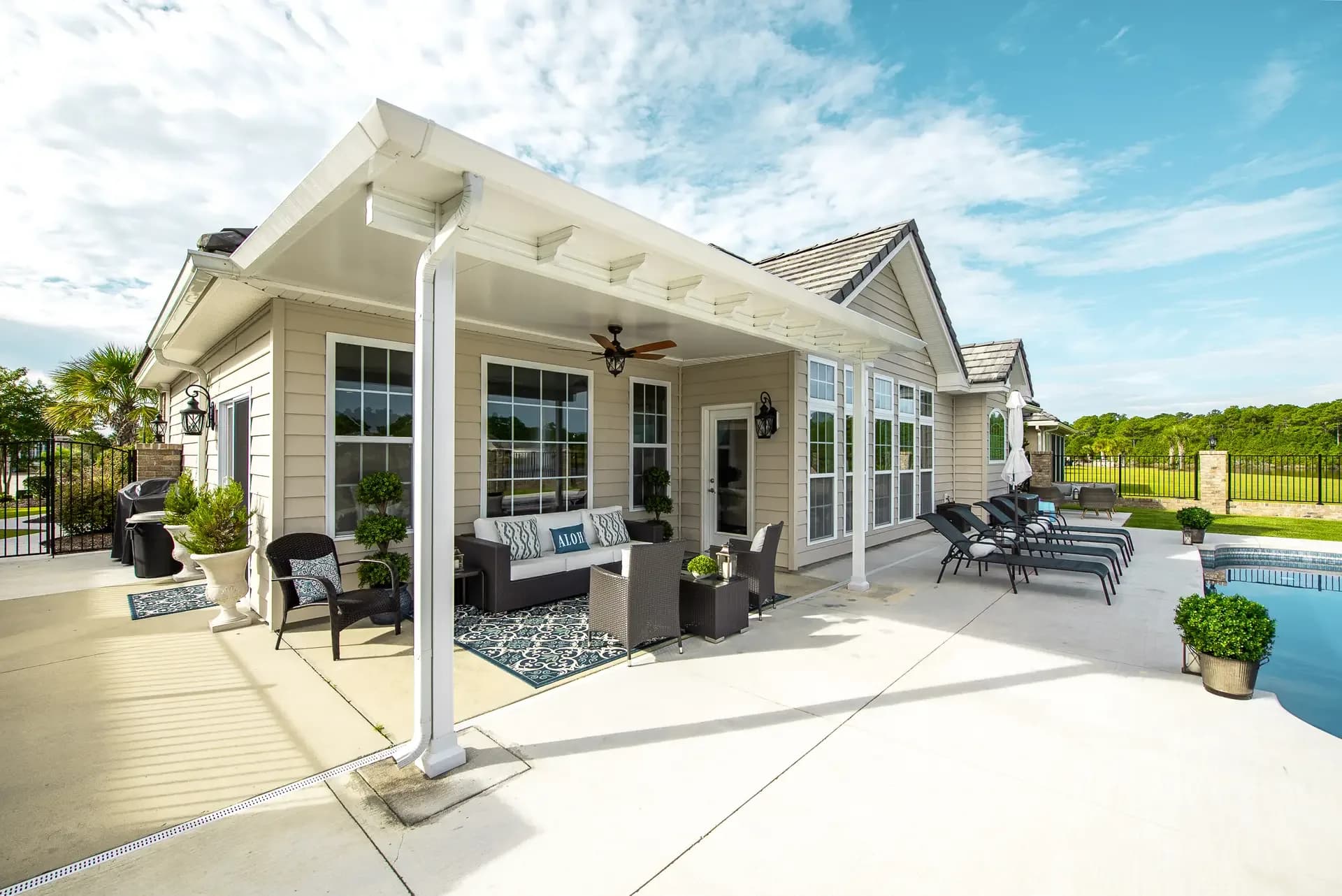 White patio cover porch with seating and the pool at right
