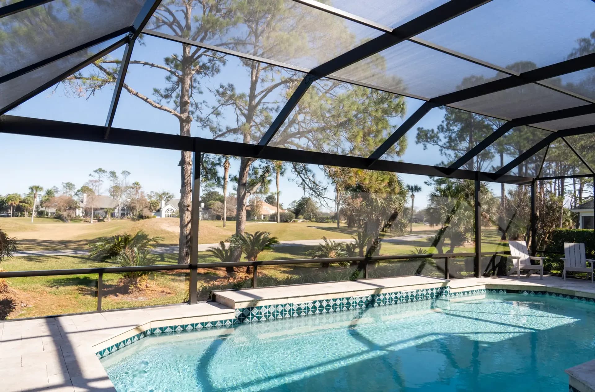 Pool inside a bronze screen enclosure overlooking a golf course fairway