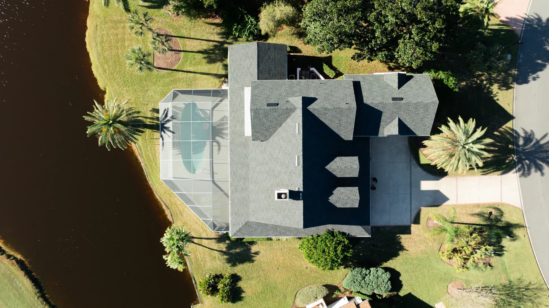 Aerial view of a lakefront home with a Screen'D In pool enclosure
