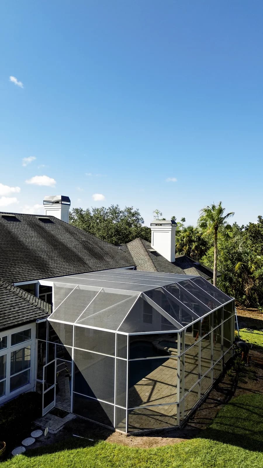 Aerial drone view of a pool enclosure rescreen over the house roof