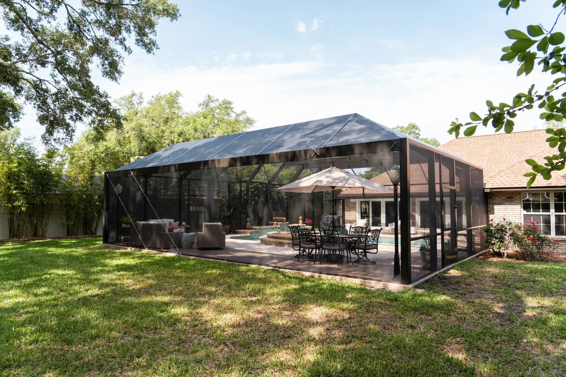 Exterior of a finished Screen'D In pool enclosure with an outdoor dining set